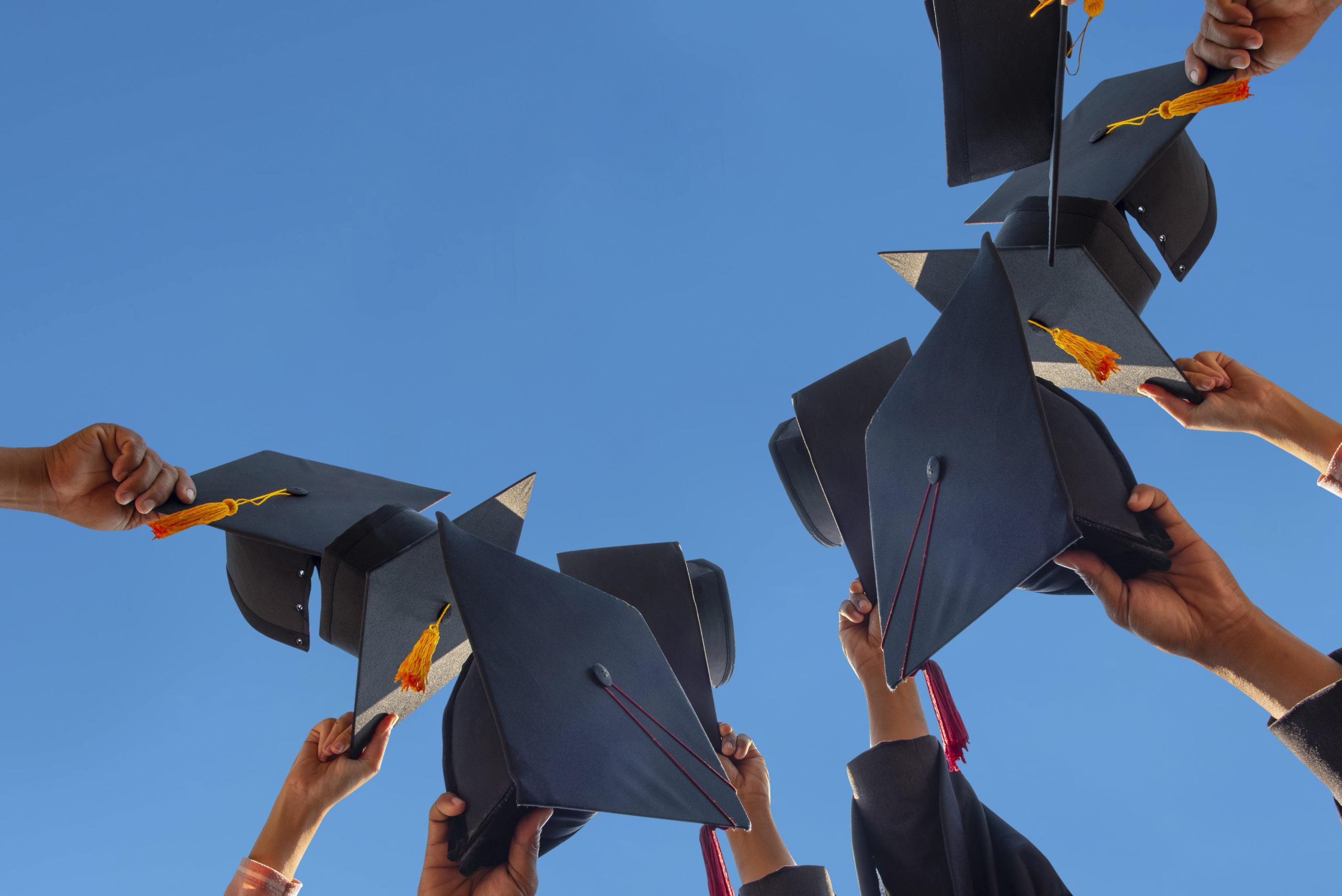 The students holding a shot of graduation cap by their hand in a bright sky during ceremony success graduates at the University, Concept of Successful Education in Hight School,Congratulated Degree